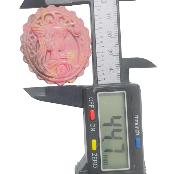 Pink rhodonite crystal carved medallion with magical girl pattern in natural light