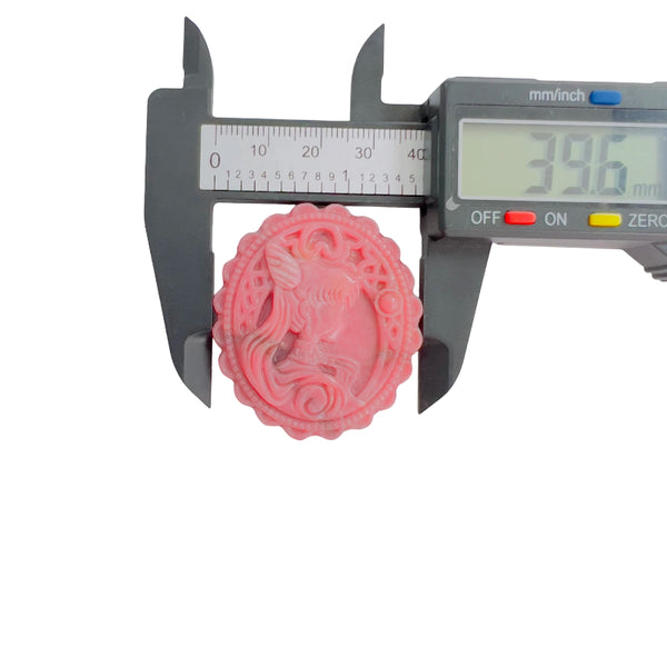 Side profile view of pink rhodonite unicorn carved medallion