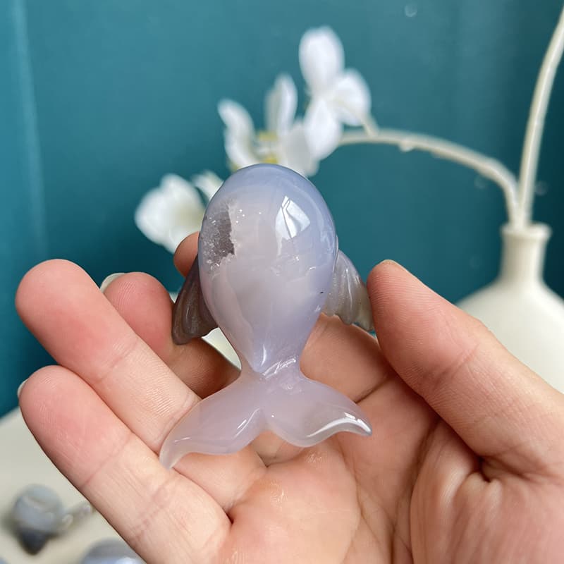 Elegant agate crystal dolphin figurine displayed on shelf with crystals