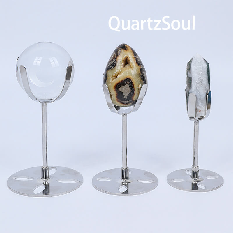 Premium silver crystal display stands showcasing clear quartz sphere, agate specimen, and crystal point