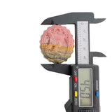 Side angle of layered rhodonite stone showing pink yellow and gray natural colors