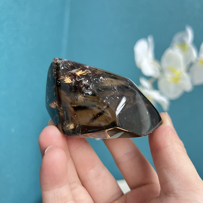 Smoky quartz free form crystal held in palm showing size