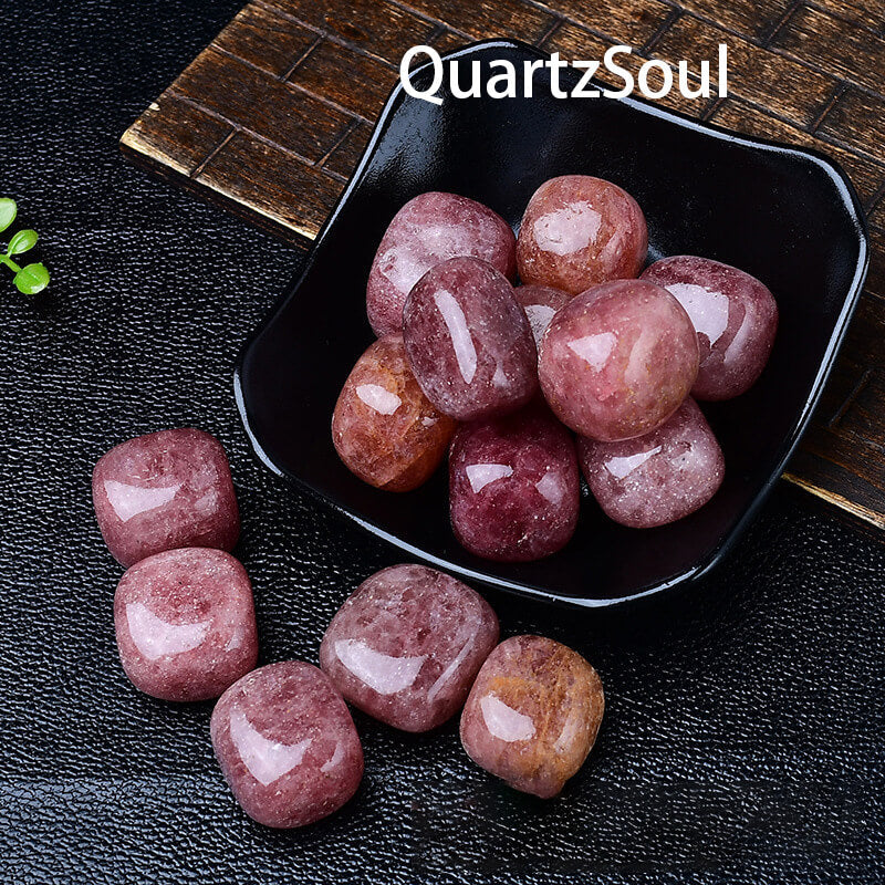 Natural strawberry quartz tumbled stones displayed in black bowl, pink polished crystals