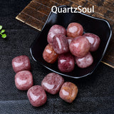 Natural strawberry quartz tumbled stones displayed in black bowl, pink polished crystals