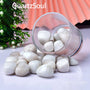Natural White Moonstone tumbled stones spilling from glass container, showing smooth polished surface and iridescent glow