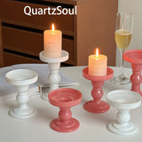White and pink crystal pillar candle stands with lit candles on table setting