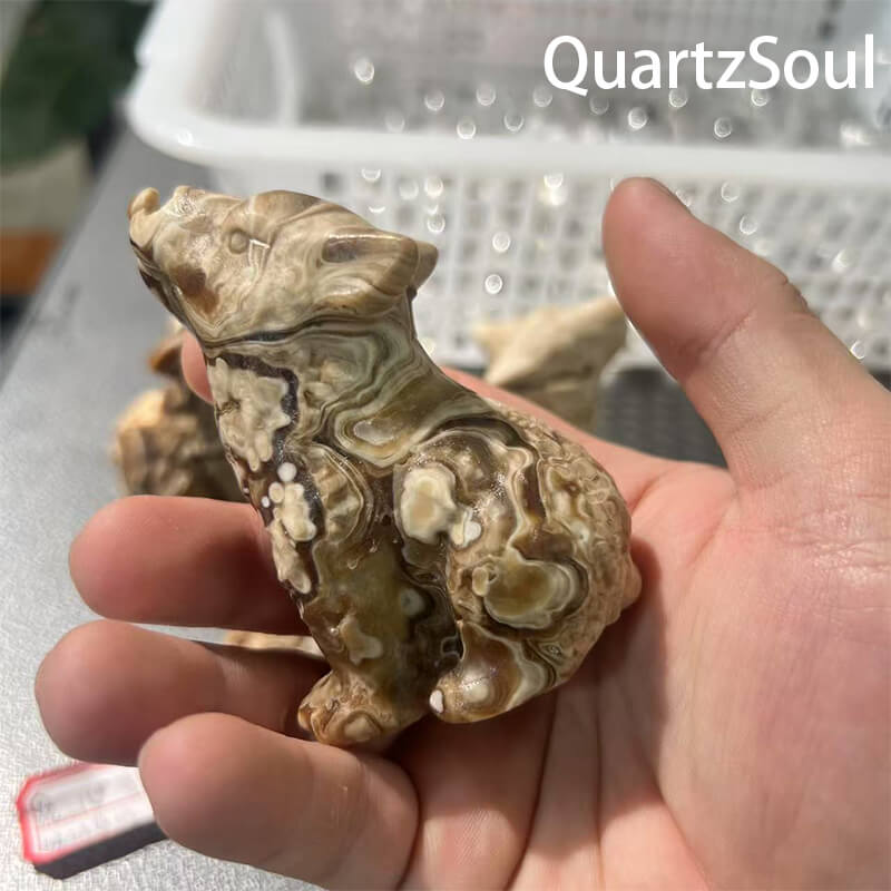 Hand holding wolf shaped chocolate calcite crystal for crystal wholesalers