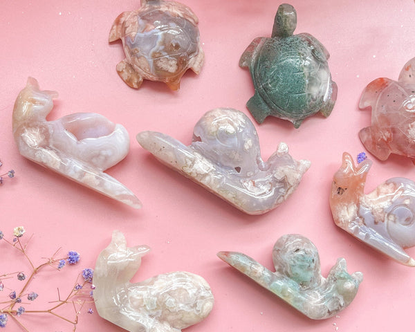 Assorted natural crystal animal carvings on pink background
