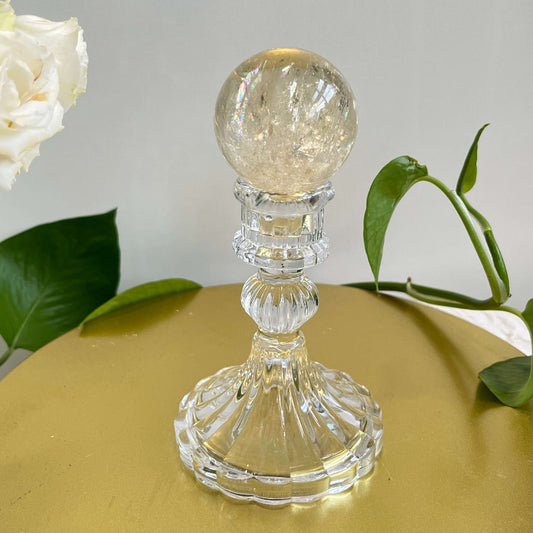Natural citrine crystal sphere with rainbow inclusions on glass display stand