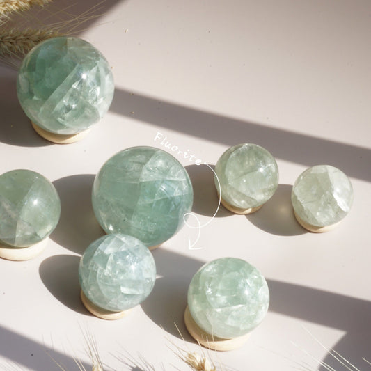 Rainbow Fluorite Crystal Sphere with purple and green bands on display stand