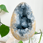 Natural raw blue celestite crystal geode with vibrant blue crystals and golden exterior