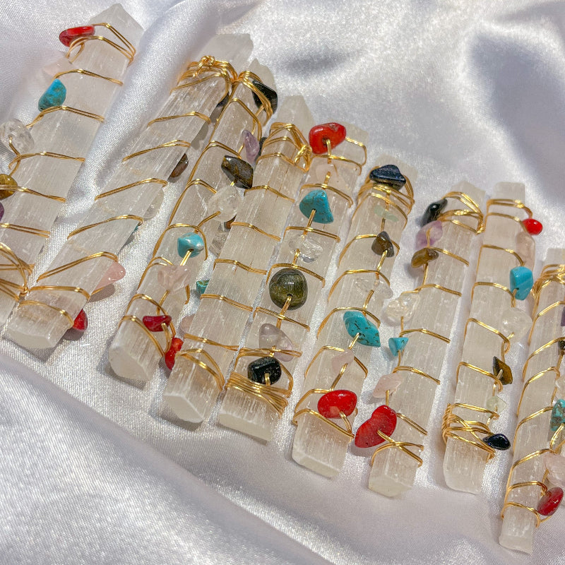 Selenite crystal wands with wire wrapped gemstone accents on white silk background