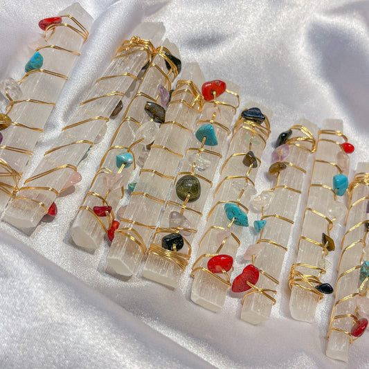 Selenite crystal wands with wire wrapped gemstone accents on white silk background
